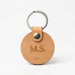 Schlüsselanhänger aus Erlenholz rund mit personalisierter Gravur auf weißem Hintergrund
