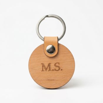 Schlüsselanhänger aus Erlenholz rund mit personalisierter Gravur auf weißem Hintergrund