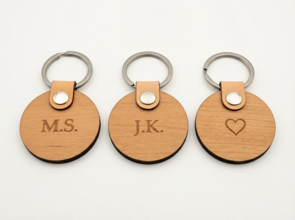 Drei runde Schlüsselanhänger aus Erlenholz mit verschiedenen Gravuren - Initialen und Herz